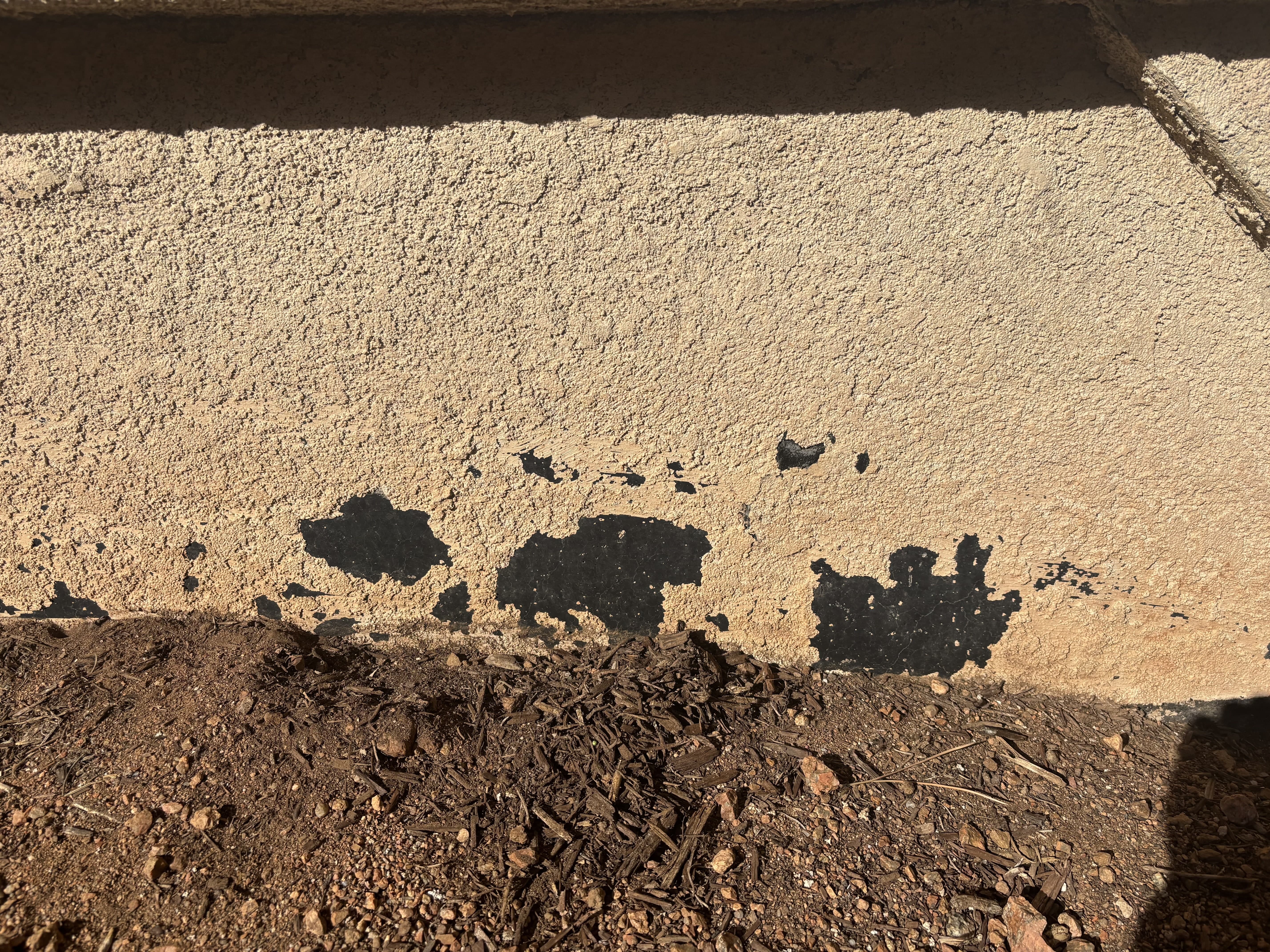 Stucco wall with peeling and damaged patches before repair